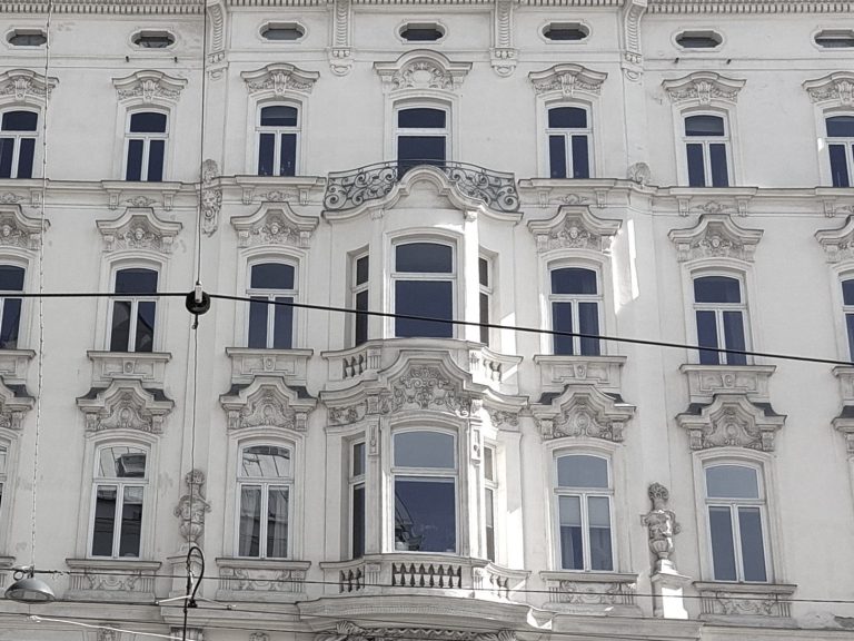 Historisches Gebäude mit verzierten Fenstern und Stuckarbeiten in Weiß.
